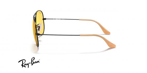 عینک آفتابی فتوکرومیک خلبانی ری بن - فریم مشکی و بخش انتهای دسته ها عسلی رنگ با عدسی زرد - عکس از زاویه کنار
